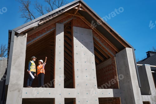 Preview: Project manager and foreman standing on high floor of almost builded house