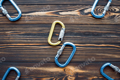 Preview: Isolated photo of climbing equipment. Parts of carabiners lying on the wooden table
