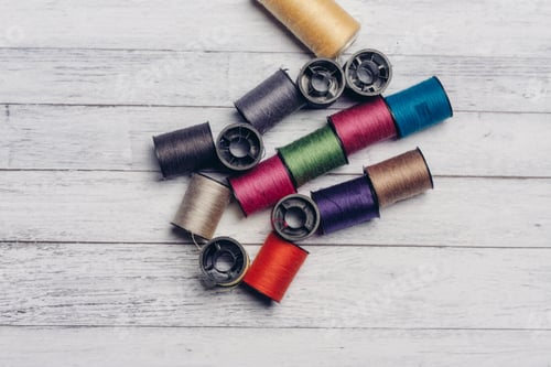 Preview: sewing accessories colored threads top view wooden background