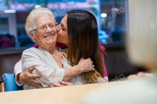 Preview: Elder woman and nurse embracing and kissing in a geriatric