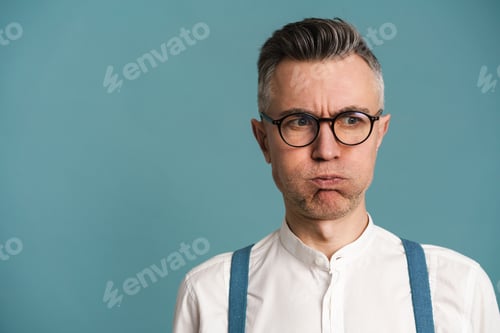 Preview: Displeased grey-haired man in eyeglasses grimacing and looking aside