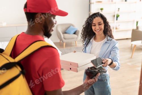 Preview: Smiling deliveryman holding POS machine, woman paying with phone