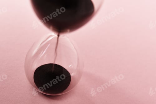 Preview: Hourglass on pink background, closeup. Urgency and running out of time concept