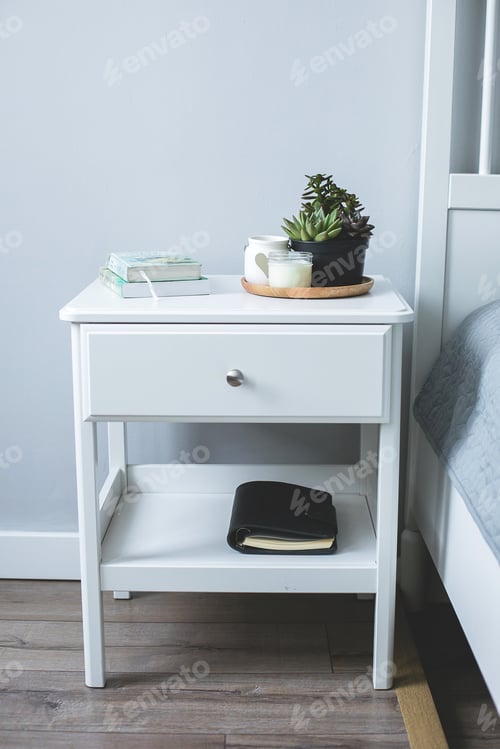 Preview: Tiny succulents, candles and black notebook on bedside table in the bedroom in scandinavian style