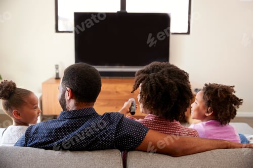 Preview: Rear View Of Family With Children Sitting On Sofa Watching TV Together