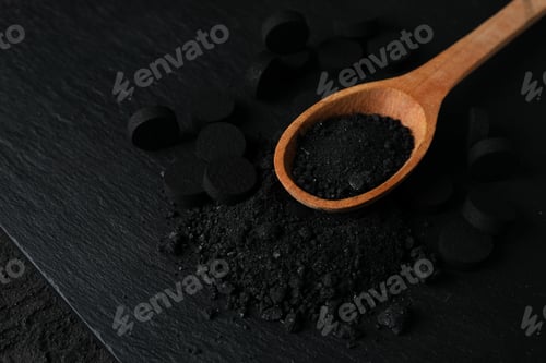 Preview: Activated charcoal powder in a wooden spoon on a dark background