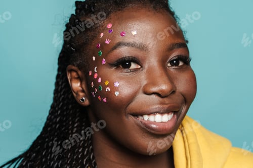 Preview: Young black woman with stickers on her face smiling at camera