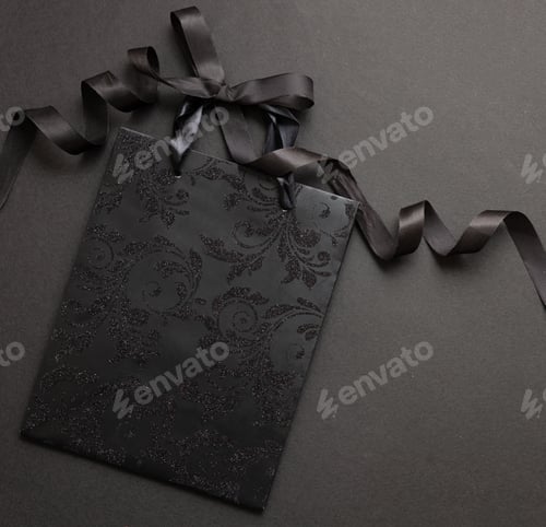 Preview: Black Friday concept. Black shopping bag on black background.