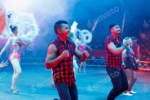 Preview: Men and women dance in the circus arena under the light of colorful lights and a fire show.