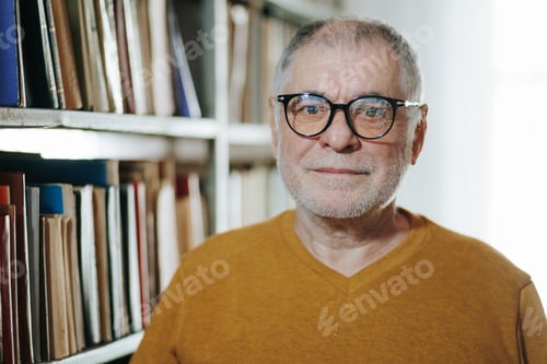 Preview: Academic Essence Front View of Senior Man with Glasses in Bookstore