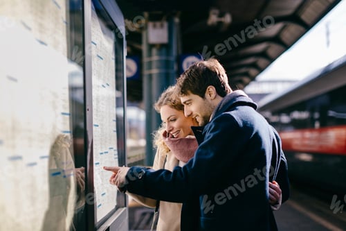 Preview: A couple cheerfully checking the train schedule at the station