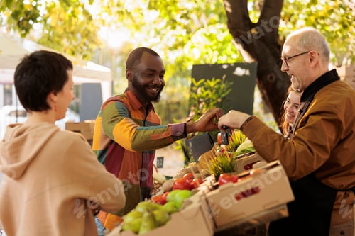 Preview: Elderly vendor giving apple sample to male customer