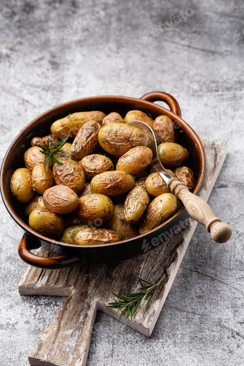 Preview: Pan filled with roasted potatoes shot on rustic wooden table.