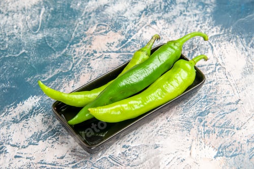 Preview: front view green hot peppers on black plate on blue-white background with free space