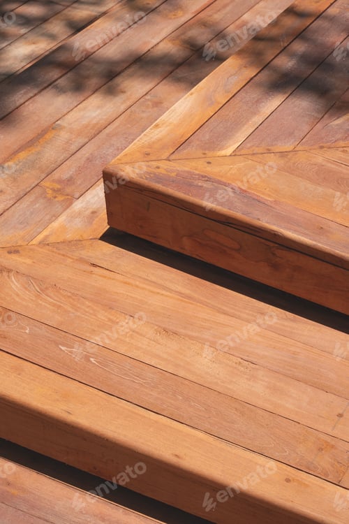 Preview: Hardwood steps of elevated walkway in public park with sunlight and tree branch shadow on surface