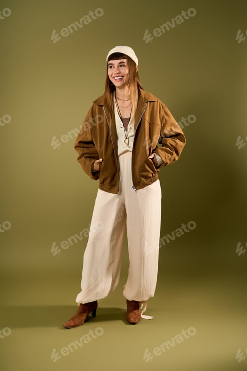 Preview: Stylish young woman in fashionable outfit poses confidently against a neutral backdrop
