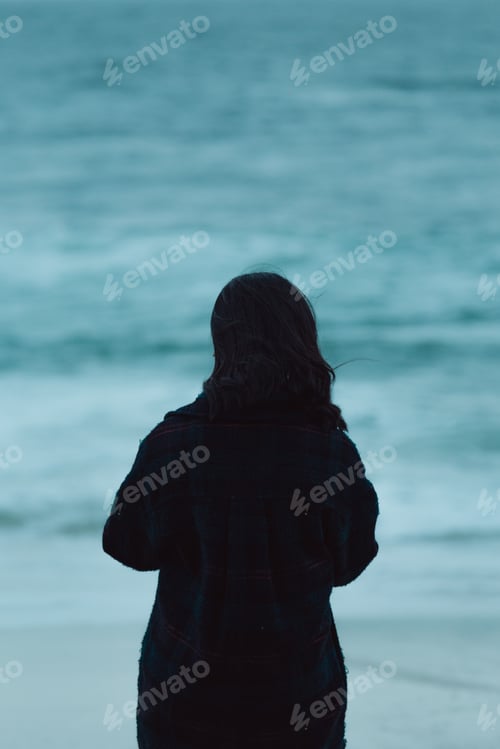 Preview: Woman giving the back to the camera in front of a massive ocean with copy space