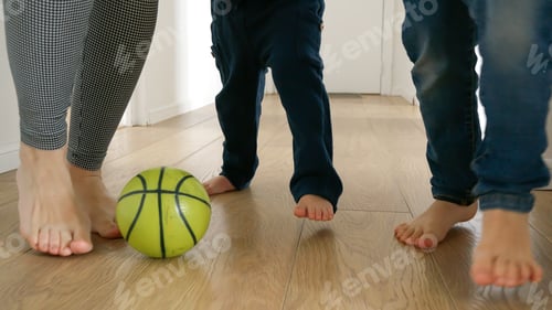 Preview: Happy family's feet as they kick a football back and forth on a wooden floor in a house corridor