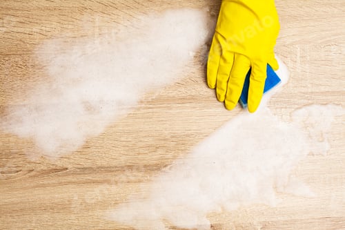 Preview: Close up of worker hand wiping dust in office in yellow gloves
