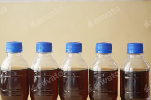 Preview: Five bottles with dark liquid and blue lids are displayed on a minimalistic background