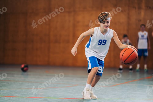 Preview: A junior basketball player dribbling a ball on training at indoor court