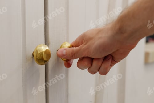 Preview: Male hand opens door of white wall cupboard.