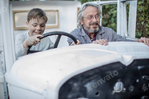 Preview: Smiling senior man and boy inside vintage car