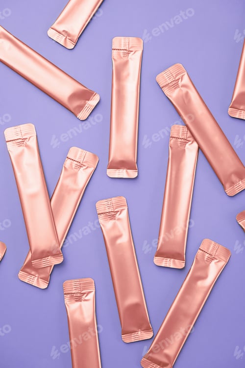 Preview: Many Rose Gold Foil Bags for Cosmetic or Food Product on Light Lavender Background.