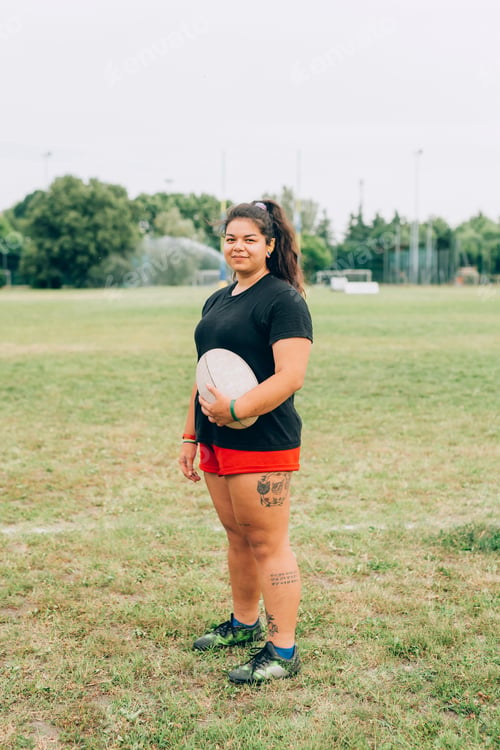 Preview: Confident rugby player holding a ball on the field.