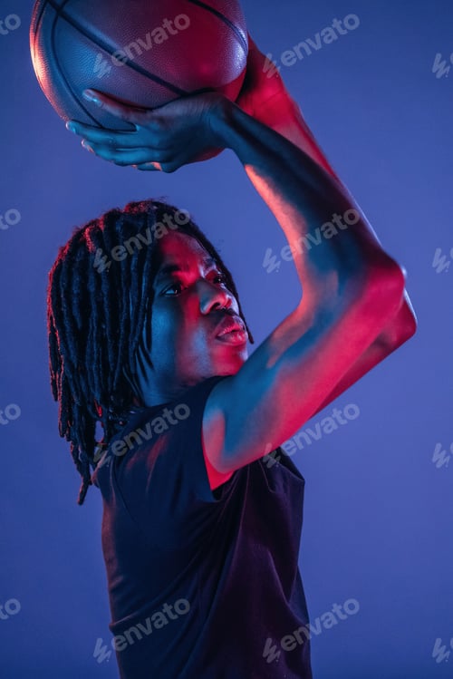 Preview: Throwing the ball. African American guy is studio with neon lighting