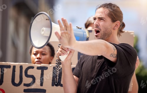 Preview: Shot of a young man with his hand raised speaking through a megaphone at a protest