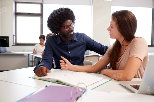 Preview: High School Tutor Giving Female Student One To One Tuition At Desk In Classroom