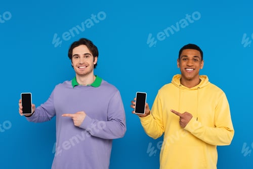 Preview: interracial friends pointing with fingers at blank screen smartphones with blank screens isolated on