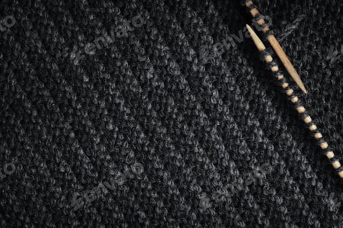Preview: Striped knitted fabric and wooden needles. Dark knitted texture background.