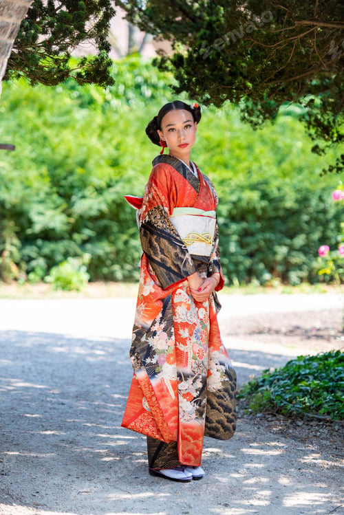 Preview: A young woman adorned in a traditional kimono standing amidst a serene garden setting.