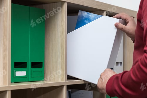 Preview: man takes folders with documents from the shelves, home-based work, work at home