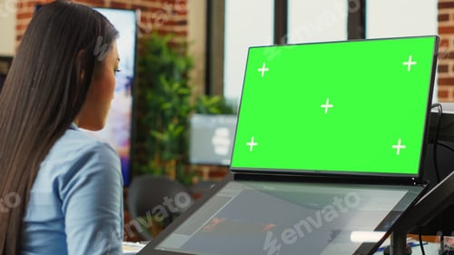 Preview: Asian woman using game developing software and greenscreen display
