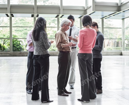Preview: A mixed race group of male and female business people standing in the lobby area of a convention