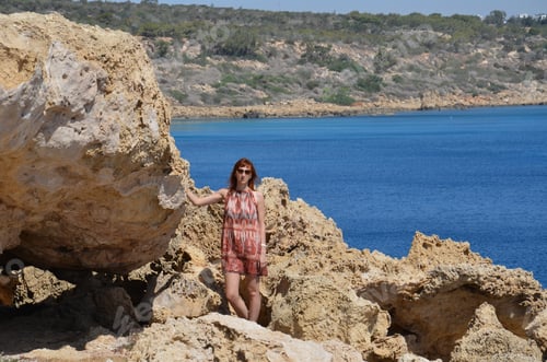 Preview: Portrait of a slender woman 30-35 years old in blue shorts and a yellow T-shirt, standing on the sea