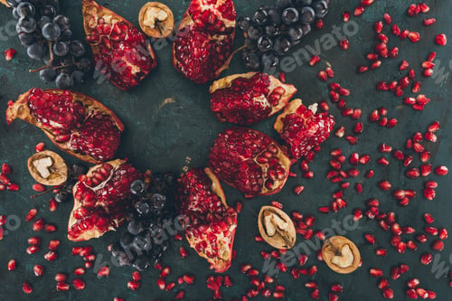 Preview: Top view of pomegranate with grapes and walnuts and scattered pomegranate seeds