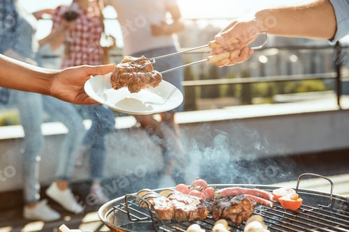 Preview: Perfect day for barbecue. Cropped photo of male hand putting hot barbecued meat on the plate while