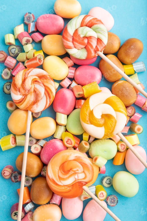 Preview: Various caramel candies on blue background. top view