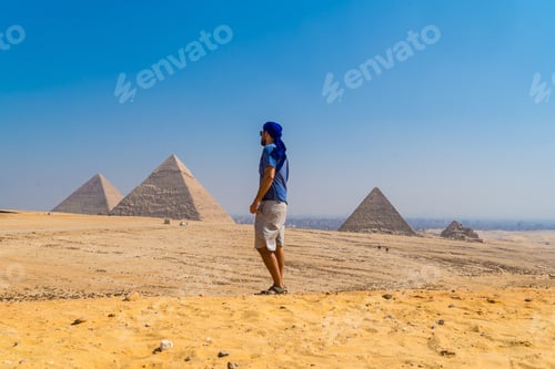 Preview: Portrait of a young man in a blue turban walking next to the Pyramids of Giza, Cairo, Egypt