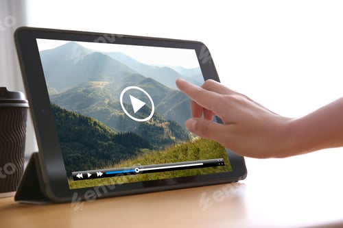 Preview: Woman watching video on tablet at wooden desk, closeup
