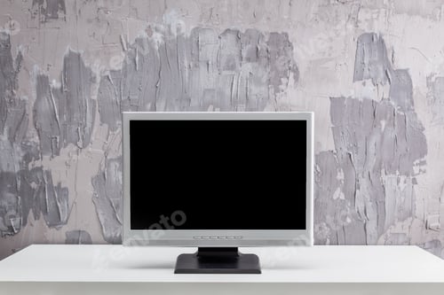 Preview: Modern minimalistic workspace featuring a blank computer monitor against a textured gray wall