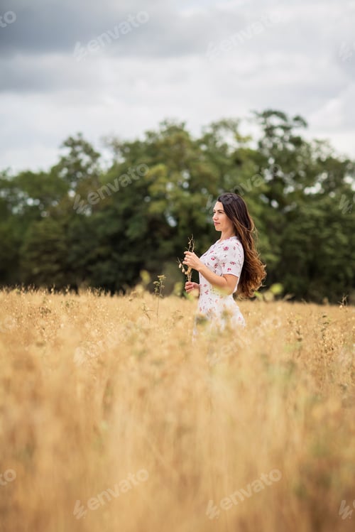 Preview: A brunette woman in a white dress runs along a field
