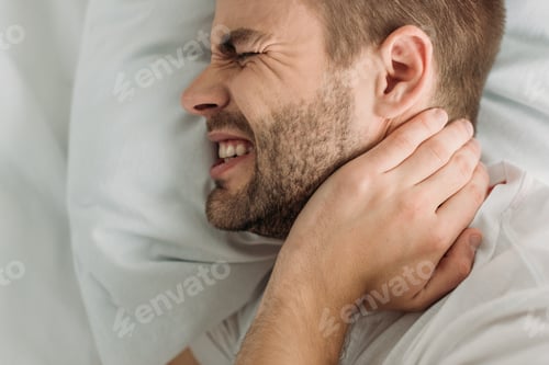 Preview: top view of young man touching neck while suffering from pain