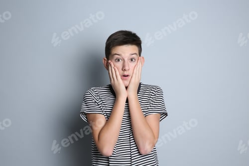 Preview: Portrait of surprised teenage boy on grey background