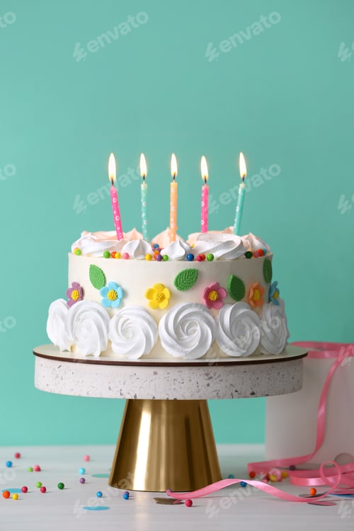 Preview: Delicious birthday cake and party decor on white wooden table against turquoise background