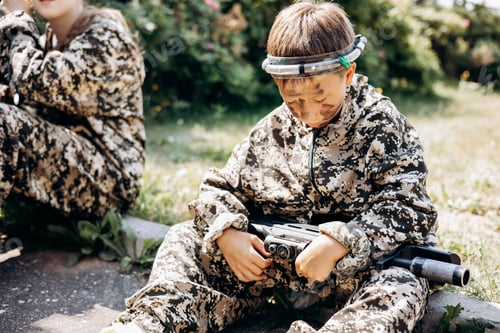 Preview: Boy with a weapon in his hand playing laser tag shooting game in outdoor. War simulation game